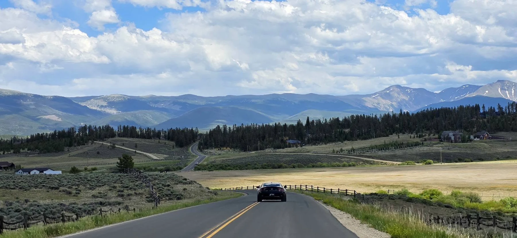 A Colorado road heading toward an expansive mountain landscape